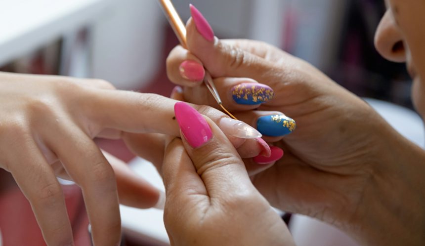 closeup of manicurist doing nail art to a client