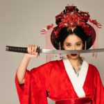 Japanese woman holding sword near face isolated on grey