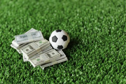 Selective focus image of soccer football and money on field.