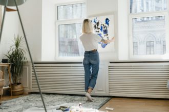 Young woman placing abstract paint on the wall