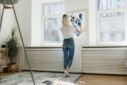 Young woman placing abstract paint on the wall